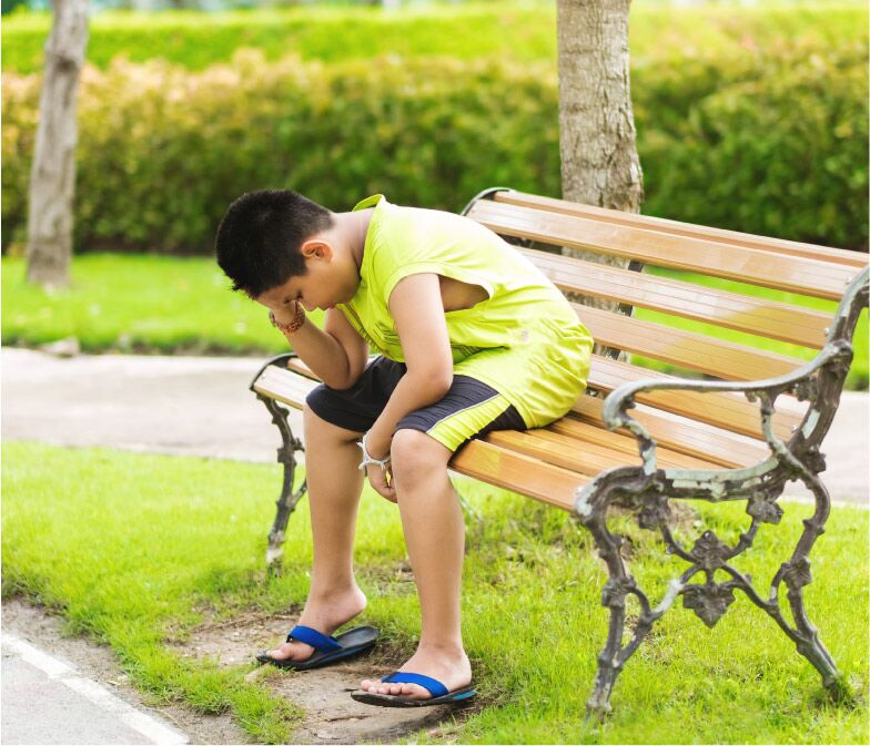 niño triste sentado en banca